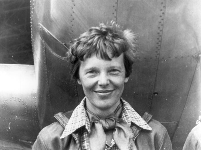 in Poster Amelia Earhart standing under nose of her Lockheed Model 10-E Electra