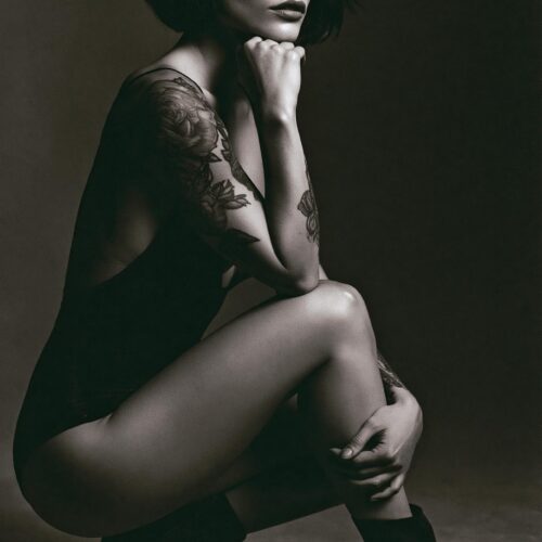Sensual black and white portrait of a tattooed woman in dramatic studio lighting
