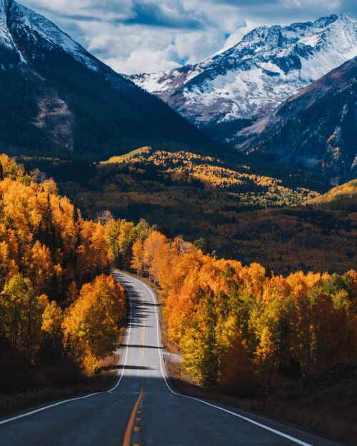 Scenic Autumn Mountain Road Wall Art – Vibrant Fall Foliage and Snowy Peaks Photography Print for Rustic Cabin or Adventure Decor picture
