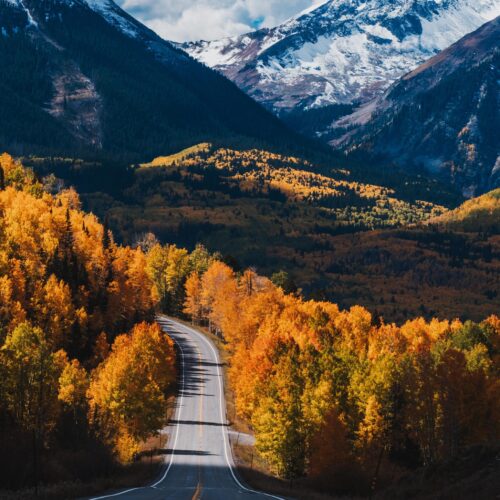 Scenic Autumn Mountain Road Wall Art – Vibrant Fall Foliage and Snowy Peaks Photography Print for Rustic Cabin or Adventure Decor picture