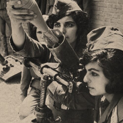 Black-and-white vintage photograph of Iranian women in military uniforms undergoing combat training with weapons during Iran-Iraq War historical period.