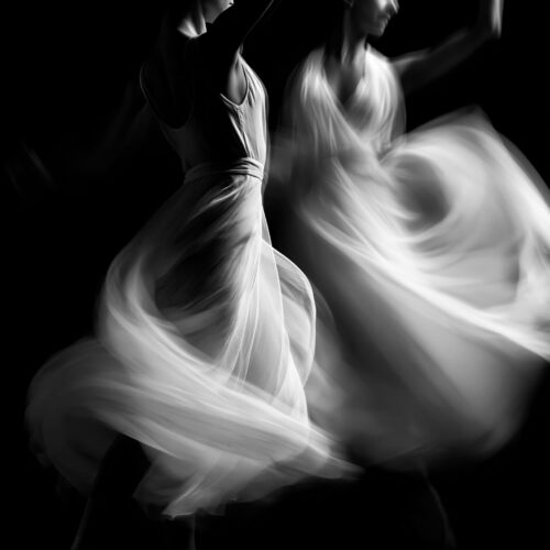 Expressionist black-and-white poster of two dancers in motion with flowing fabric and ethereal blur effects against a dark background.