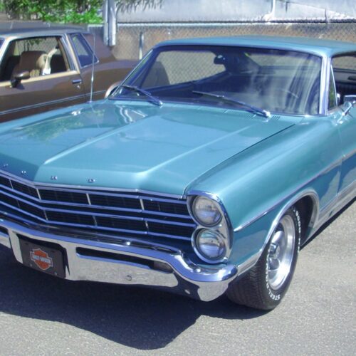 Retro Ford Galaxie Coupe muscle car in turquoise and chrome, photographed at a car show with sharp detail and vibrant color.