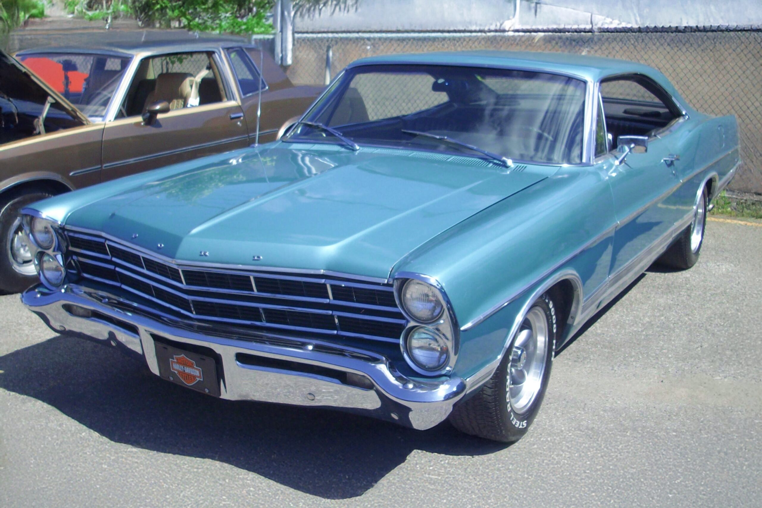 Retro Ford Galaxie Coupe muscle car in turquoise and chrome, photographed at a car show with sharp detail and vibrant color.