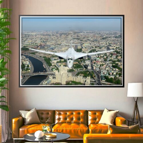 White Tupolev Tu-160 supersonic bomber flying above Moscow cityscape with river, historic architecture, and sprawling urban landscape below.