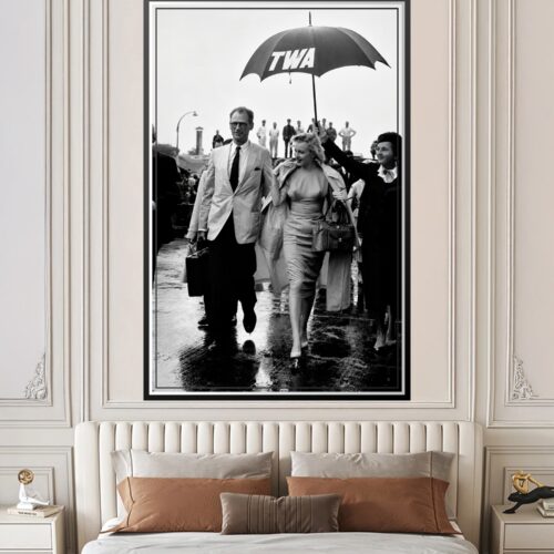 Black-and-white vintage photograph of Marilyn Monroe and Arthur Miller walking under a TWA umbrella at London airport in 1956, iconic Hollywood wall art poster.