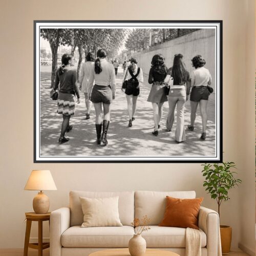 Black-and-white vintage photograph of stylish women walking down a sun-dappled urban street with trees and buildings, evoking mid-century street fashion.